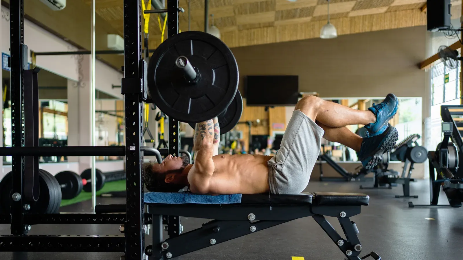 Person som utför bänkpress med skivstång i ett gym