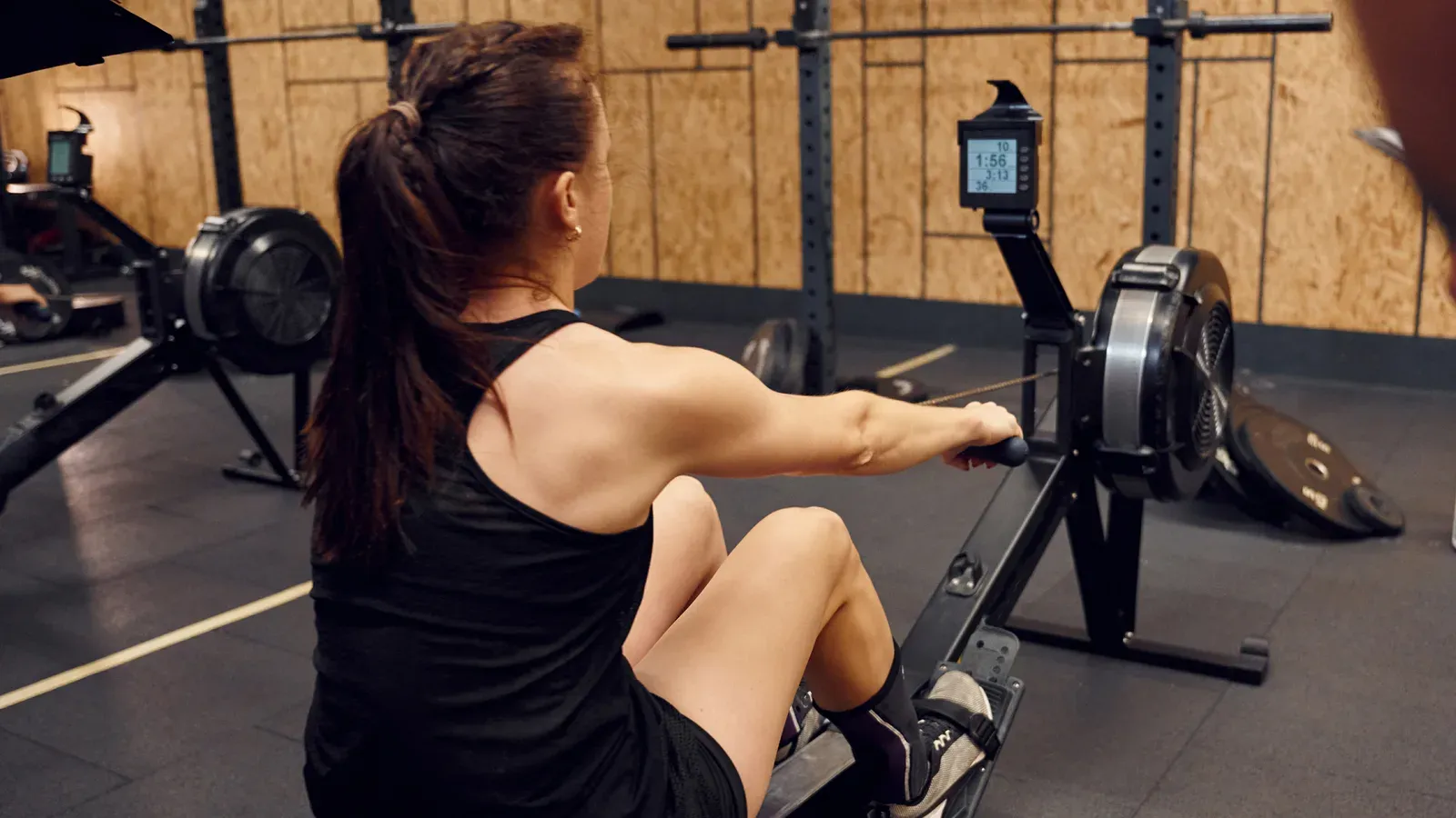 Kvinna som drar i handtaget på en roddmaskin i ett gym
