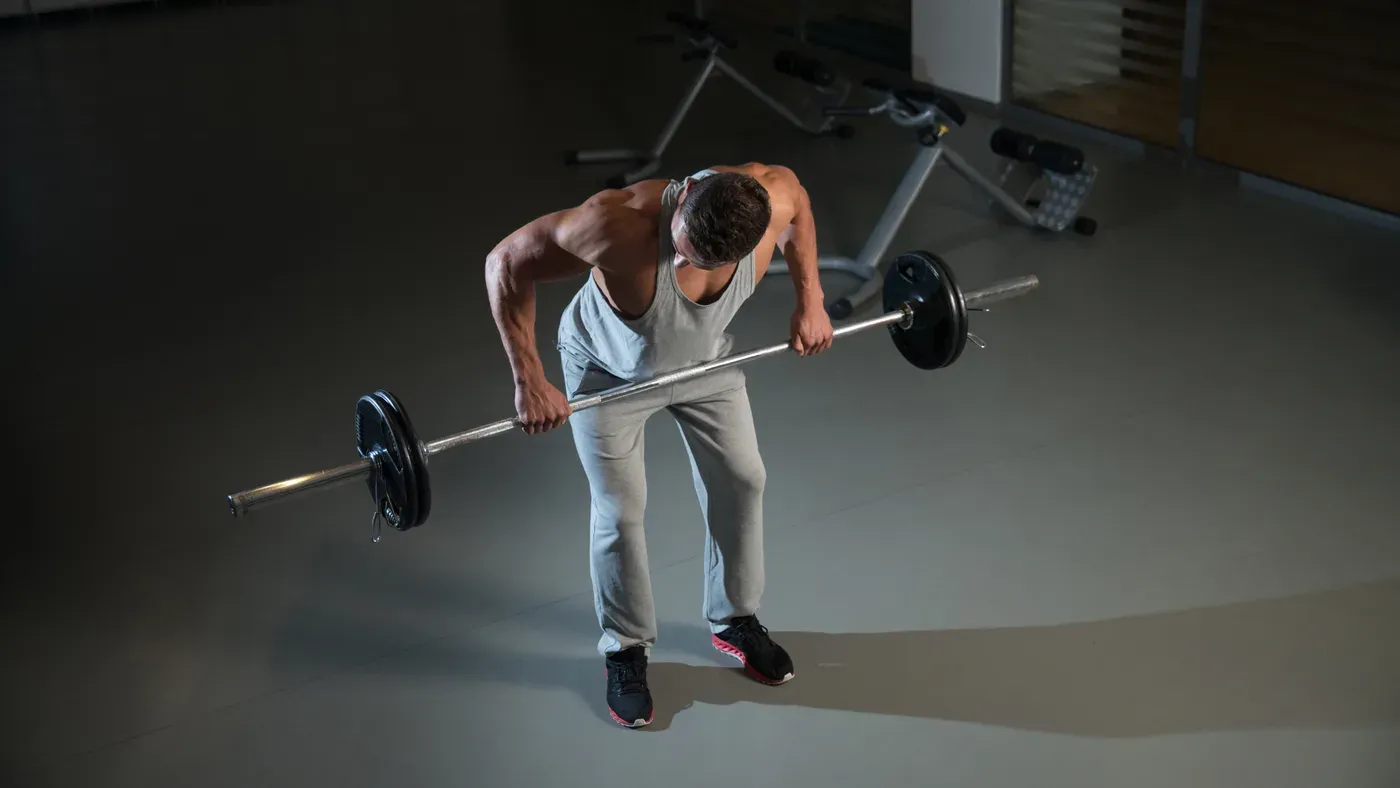 Person som utför skivstångsrodd i ett gym